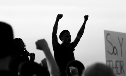 La silhouette d&rsquo;un homme levant les poings au milieu d&rsquo;une foule qui manifeste