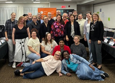 Les agentes de programme, les coordonnatrices r&eacute;gionales et les nouveaux facilitateur&middot;rices sourient devant une banni&egrave;re du PAM.